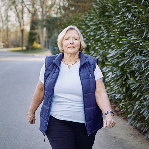 Woman walking outside wearing her Eversense CGM with glucose sensor technology. 