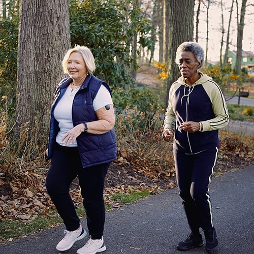 Two women with Eversense CGM devices walking outdoors. 