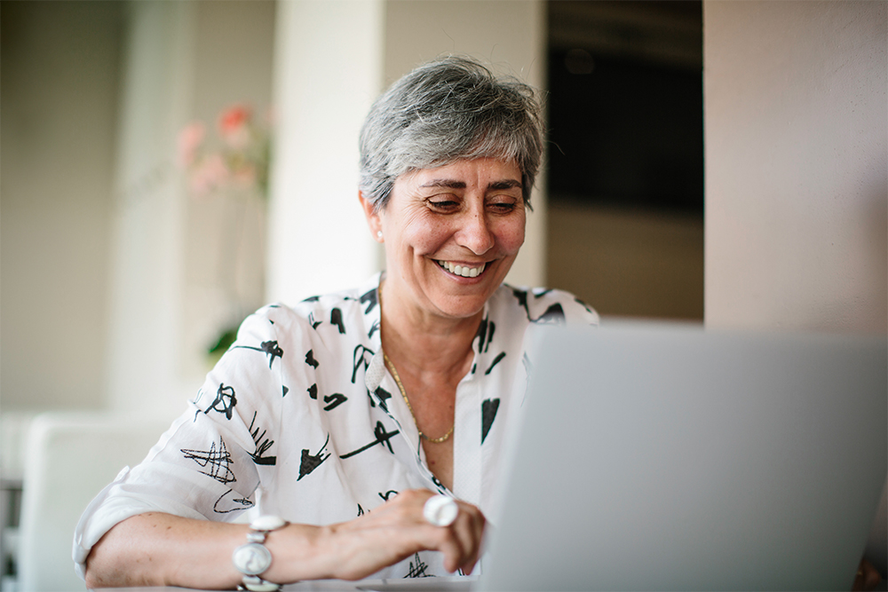 Woman using her laptop to research the wireless glucose monitor CGM app. 