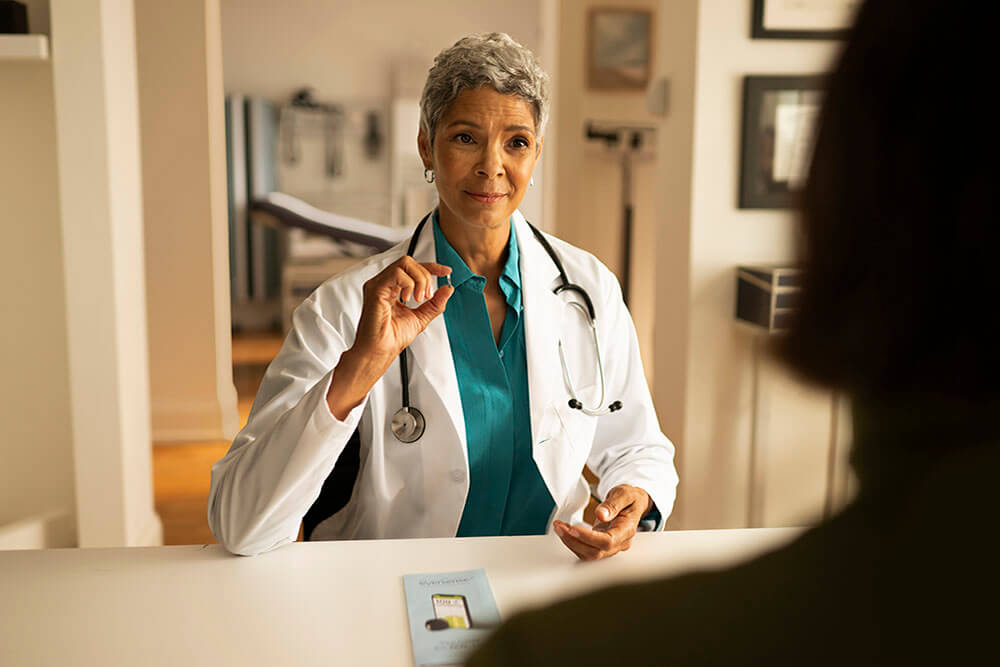 Woman using her phone to research coverage for an implantable CGM. 